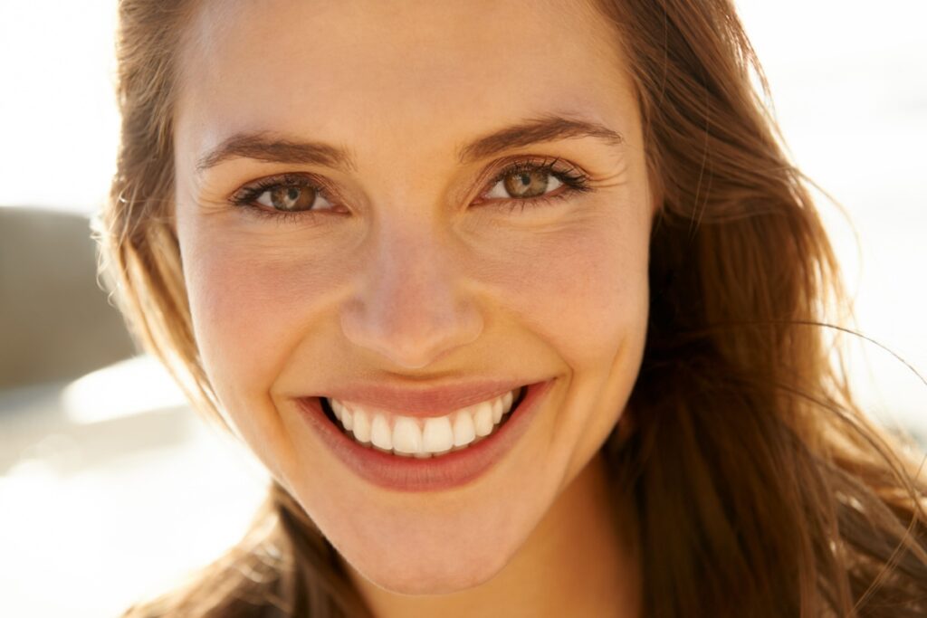 Woman smiling with sun light behind her.