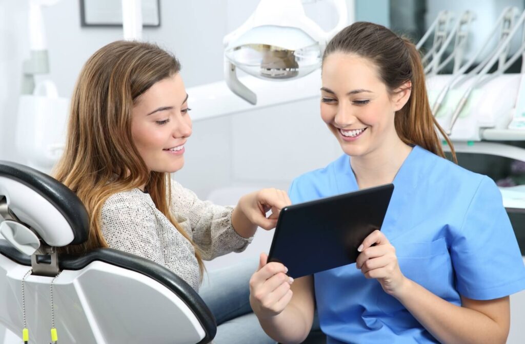 Dental hygienist showing a young adult female patient a tablet with her dental information.